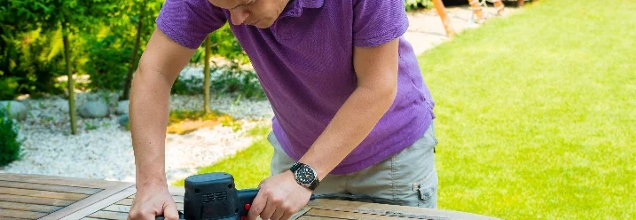 Person schleift Holztisch mit Schleifer